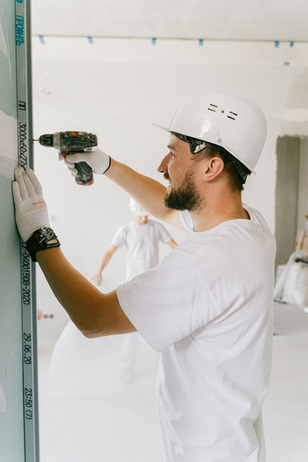 Contractor in hard hat drilling into a wall on an interior build — marketing for general contractors
