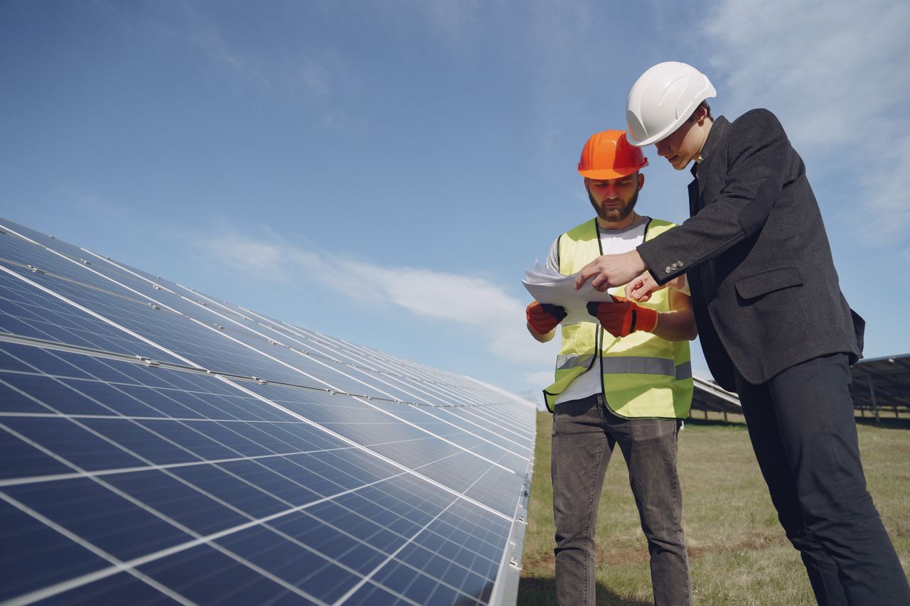 Solar installer reviewing plans beside a photovoltaic array — solar contractor marketing